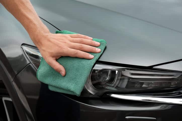 Man washing car headlight with rag, closeup