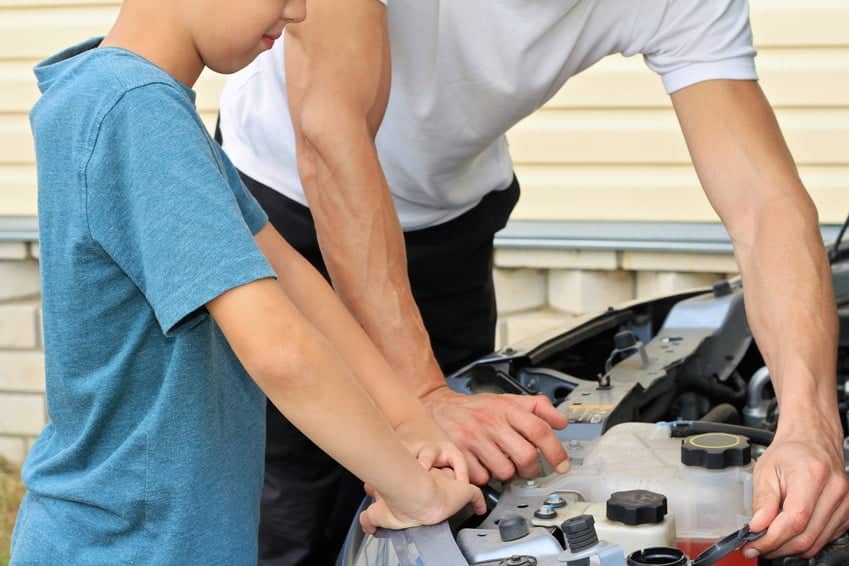 Father teaching son how to repair the car.