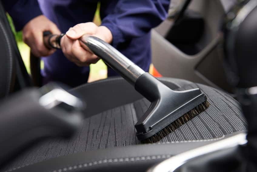 Man hoovering seat of a car