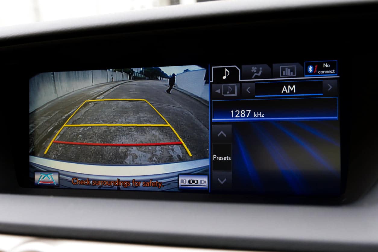 A stock photo of an in dash reversing camera showing the view of a suburban driveway.