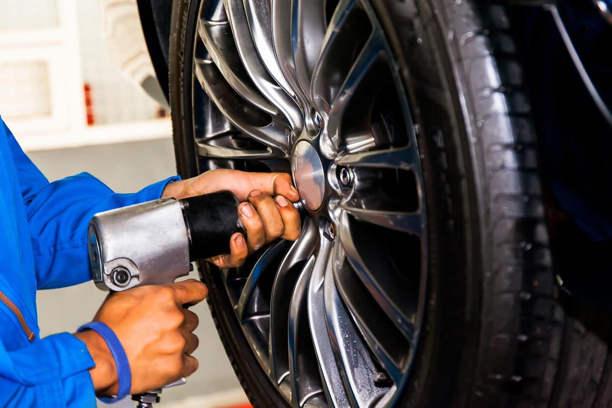 mechanic screwing or unscrewing car wheel at car service garage