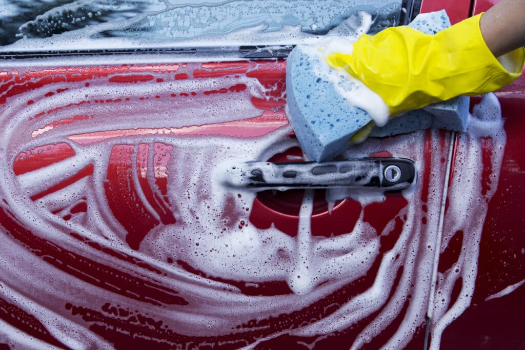 person washing car with shampoo and sponge