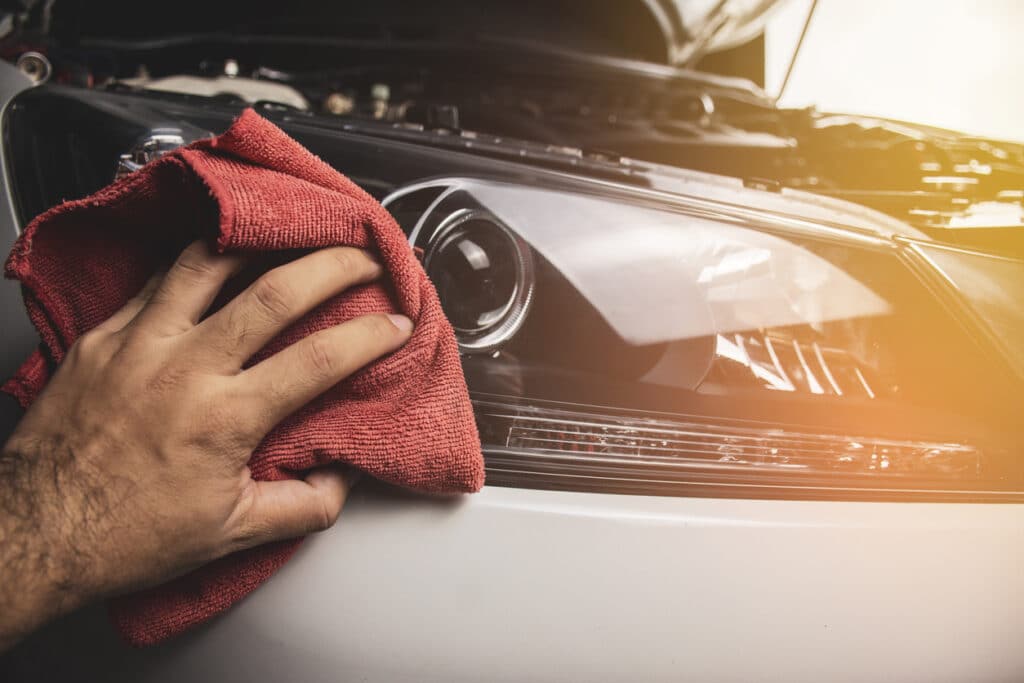 Hand is cleaning car headlight with a using red microfiber cloth,Automotive maintenance concept.