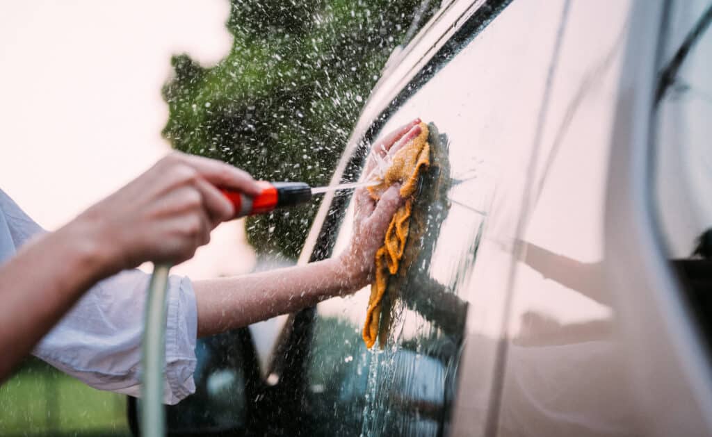 Cropped image of hands washing a car window