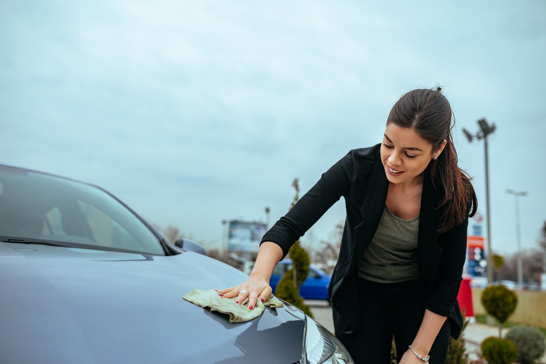 Shot of a young woman cleaning her car